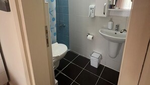 Un baño con inodoro, lavabo y zona de ducha.