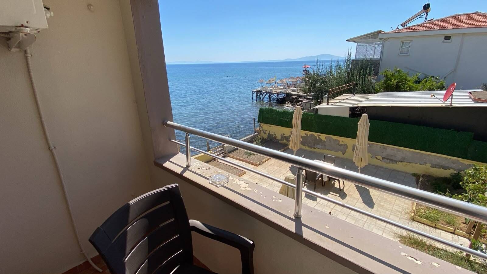 A balcony with a view of the sea, a chair, and a table.