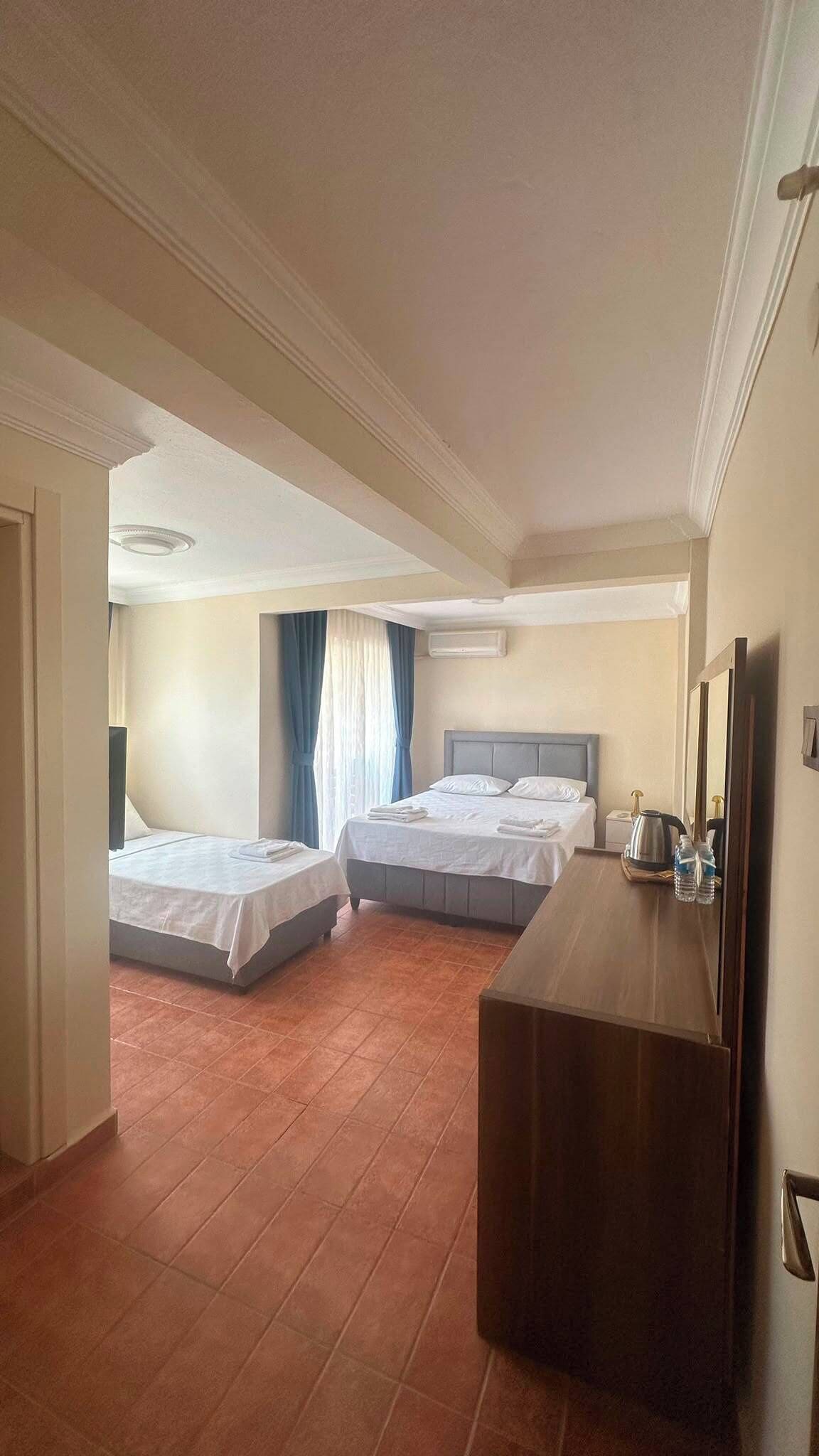 A hotel room with two beds, a wooden dresser, a mirror, and a ceiling light.