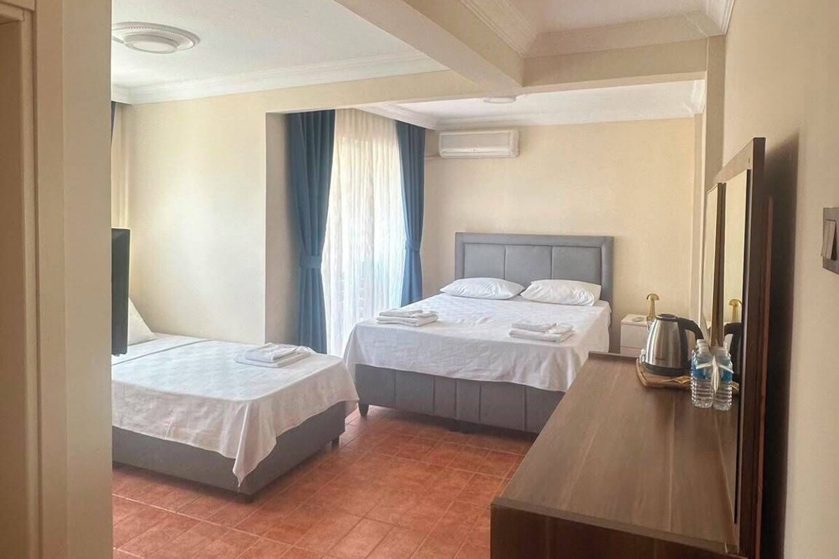 A hotel room with two beds, a wooden dresser, a mirror, and a ceiling light.