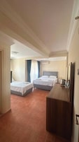 Habitación de hotel con dos camas, un aparador de madera, un espejo y una lámpara en el techo.