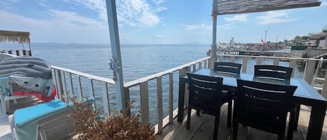 A wooden deck with a table and chairs, overlooking a body of water.