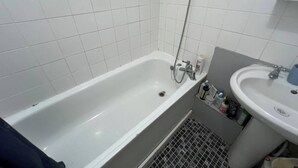Un bagno con una vasca da bagno bianca, un lavandino e un soffione.