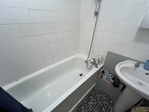 Ein Badezimmer mit einer weißen Badewanne, einem Waschbecken und einer Duschbrause.