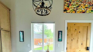 A dining area with a wooden table, white chairs, a hanging light fixture, and a view through a glass door. - Hermosa Meadows Hideaway - 360° Red Cliff Views, Sleeps 5, 10 min to Durango (Durango)