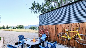 An outdoor seating area with a fire pit, chairs, and bicycles against a wooden fence. - Hermosa Meadows Hideaway - 360° Red Cliff Views, Sleeps 5, 10 min to Durango (Durango)
