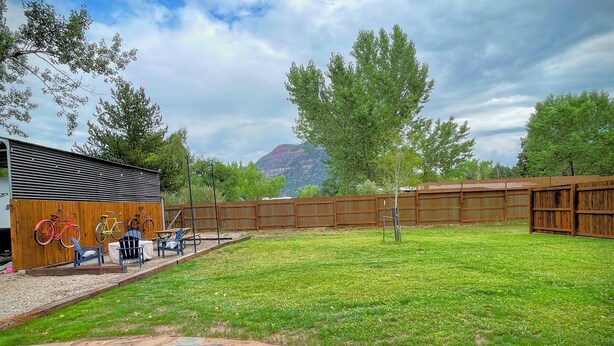 A fenced outdoor area with a wooden building, a stone pathway, and a grassy lawn. - Hermosa Meadows Hideaway - 360° Red Cliff Views, Sleeps 5, 10 min to Durango (Durango)