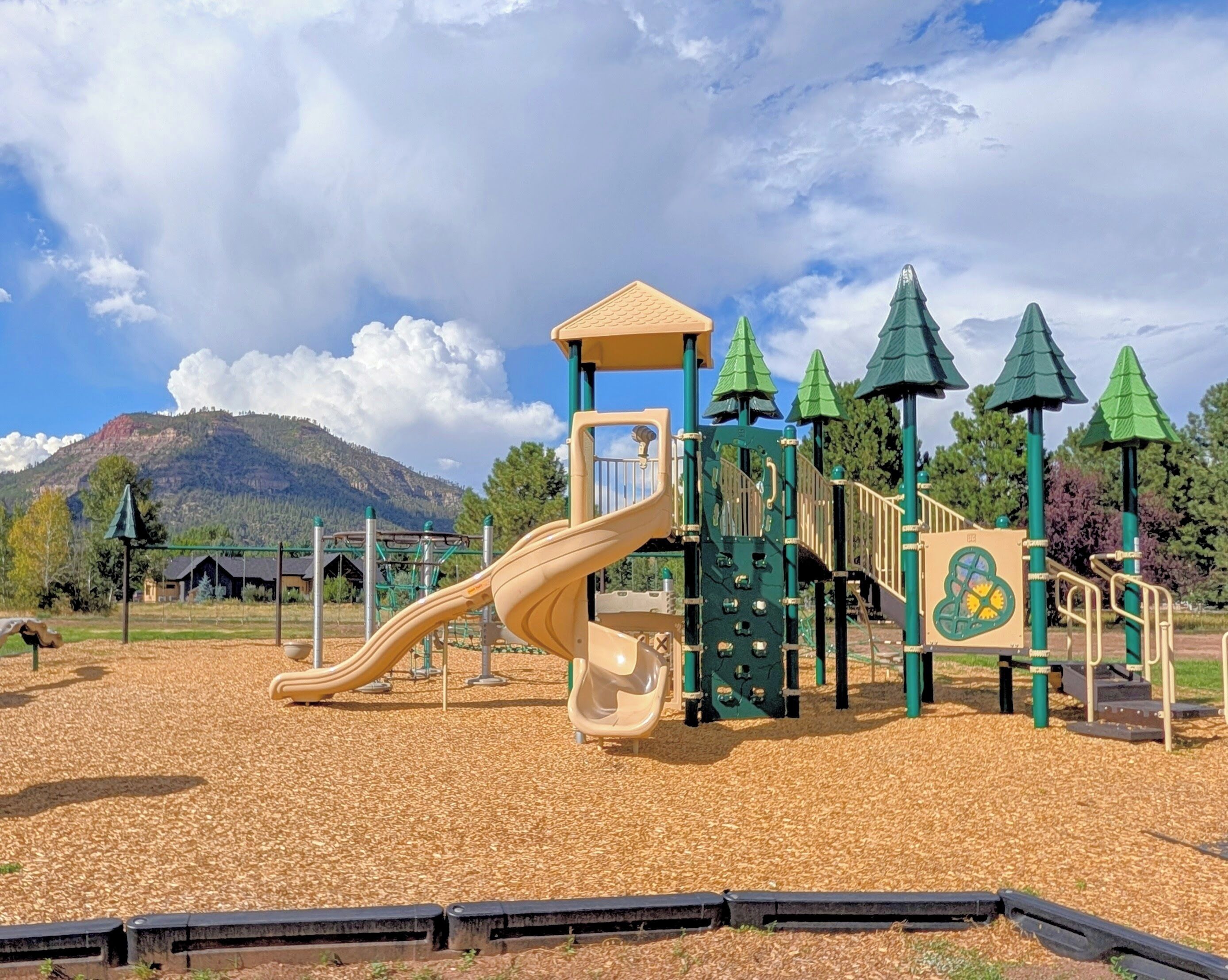 A playground with a slide, climbing structures, and a covered area.