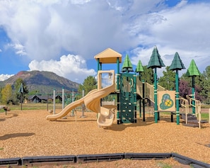 A playground with a slide, climbing structures, and a covered area.
