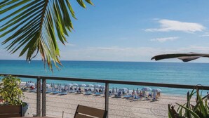 A beach view with umbrellas and lounge chairs, a palm tree, and a clear sky. - Gorgeous Intracoastal - 2BR Upper Beachwalk Suite (Hallandale Beach)