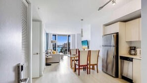 A modern kitchen with a stainless steel refrigerator, a coffee maker, and a dining area with a table and chairs. - Gorgeous Intracoastal - 2BR Upper Beachwalk Suite (Hallandale Beach)