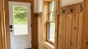 A hallway with a stone floor, wooden walls, a bench, and a door leading outside. - Luxury Stowe Home w/ Sauna & Hot Tub (Stowe)