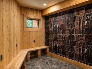 Una habitación de madera con un banco, una ventana y una pared decorada con varios objetos.