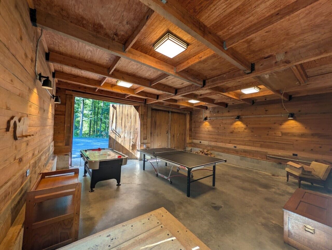 A wooden interior with a ping pong table, a foosball table, and a billiards table.
