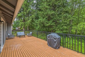 Eine Holzterrasse mit Gartenmöbeln und einem Grill.