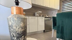 Een moderne keuken met witte kasten, een inbouwoven en een groene stoel.