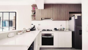Uma cozinha moderna com armários brancos, uma geladeira preta e um forno embutido.
