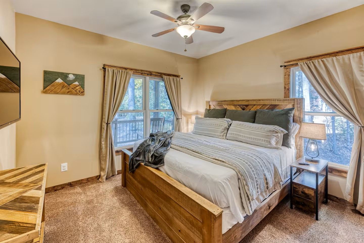 A bedroom with a wooden bed, a ceiling fan, and a view of the outdoors through a window.