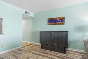 A room with teal walls, a dark wooden cabinet, and a sign that reads 'BESNICS'. - Beachfront Paradise with Stunning Gulf Views, Island Echo Condo (Fort Walton Beach)