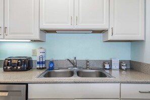 A kitchen with white cabinets, a double sink, a toaster, and a bag of paper towels. - Beachfront Paradise with Stunning Gulf Views, Island Echo Condo (Fort Walton Beach)