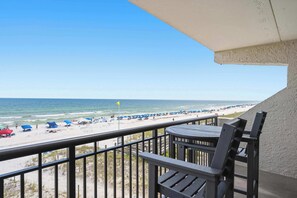 A balcony with a view of a beach, featuring a table and chairs, and a railing. - Beachfront Paradise with Stunning Gulf Views, Island Echo Condo (Fort Walton Beach)