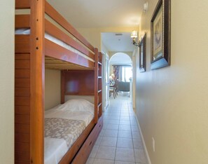 A narrow hallway with a bunk bed on the left and a dining area in the background. - Disney Dreams Apartment Amazing Lake Views! (Orlando)