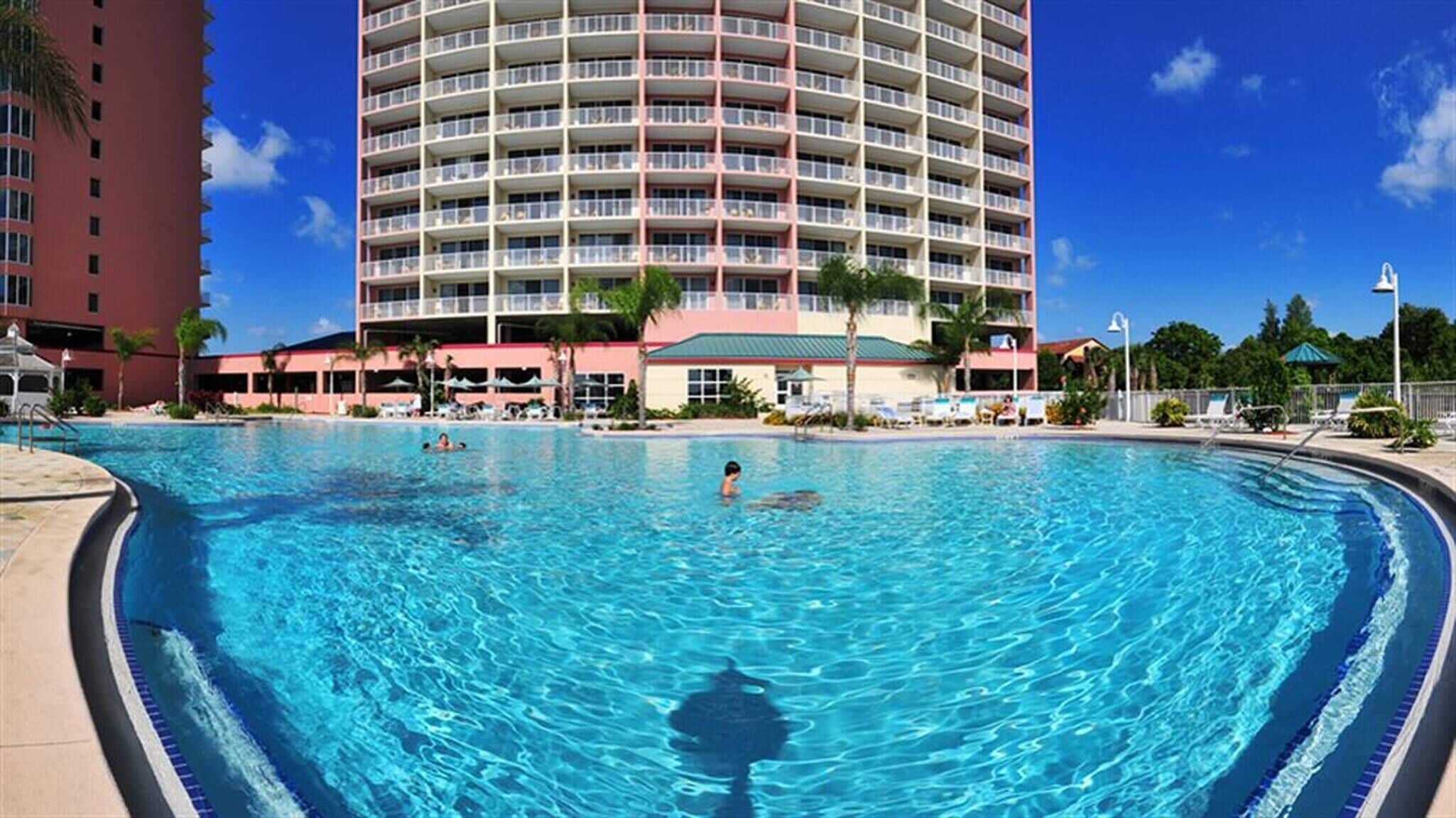 Une grande piscine avec vue sur un immeuble d’hôtel à plusieurs étages en arrière-plan.