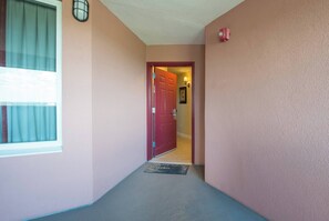 A hallway with a red door, a window with curtains, a wall-mounted light fixture, and a doormat. - Disney Dreams Apartment Amazing Lake Views! (Orlando)