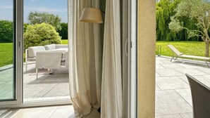 Un patio exterior moderno con puerta corrediza de vidrio, un sofá blanco y una lámpara.