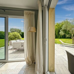 Eine moderne Terrassengrundstück mit einer Schiebetür, einem weißen Sofa und einer Lampe.