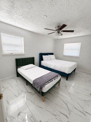 Ein Schlafzimmer mit zwei Betten, einem Deckenventilator und weißem Marmorboden.