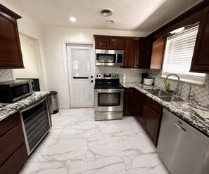 A kitchen with a white door, stainless steel appliances, and a marble floor. - Villa Montalvo | Luxury retreat + pool table | Piano (Odessa)