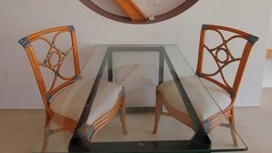 A dining area with a glass-top table and two wicker chairs. - Bamboo Suite for 2 people, FREE parking (Rapallo)