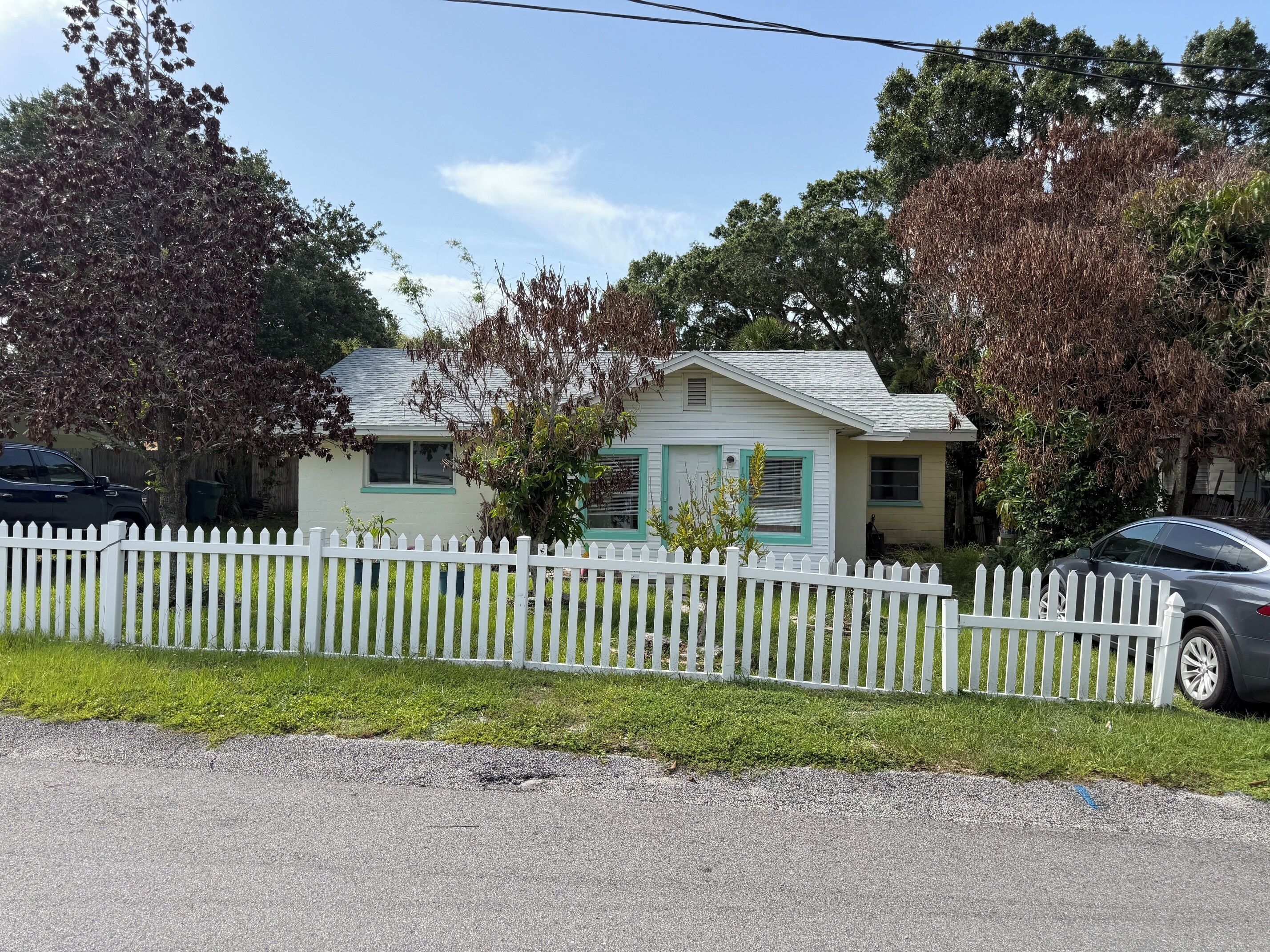 Une maison de plain-pied avec une clôture en bois peinte en blanc, un garage et une allée.