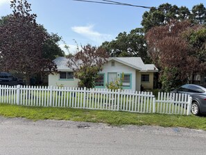 Ein eingeschossiges Haus mit weißem Zaun, einer Garage und einer Auffahrt.