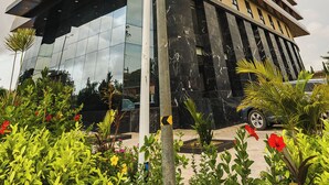 A modern building with a glass facade, multiple floors, and a street sign indicating the intersection of K.A. Ofori Atta St. and N.I. Nyanghi St. - Modern Studio Apt with Balcony near Airport in Accra with AC, Pool + Gym access (Accra)