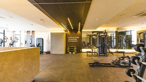 A modern gym with various exercise equipment, a reception desk, and a motivational wall. - Modern Studio Apt with Balcony near Airport in Accra with AC, Pool + Gym access (Accra)