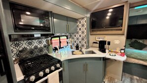 Een praktische kitchenette met een magnetron, fornuis en koffiehoek.