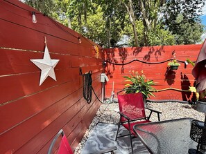 Eine rote Holzwand mit weißer Sterndeko, ein roter Stuhl und eine hängende Pflanze.