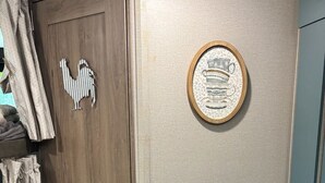 Een kamer met een houten deur, een lijst met decoratie aan de muur, en een blauwe kast.