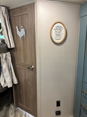 Ein Zimmer mit einer Holztür, einer gerahmten Wanddekoration und einem blauen Schrank.