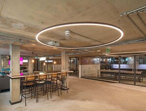 Eine moderne Bar mit einer runden Lampe, Barhocker und einer Sitzecke mit einer Couch.