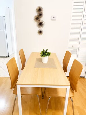 A conference room with a wooden table, four chairs, a potted plant, and decorative wall art. - Spacious Miami Beach 1BR • Beach Access • Sleeps 3 (Miami Beach)