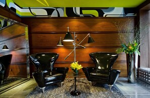A modern interior with two black chairs, a floor lamp, and a vase with yellow flowers. - Moderne | Deluxe King | Broadway Theatre District | Pet-Friendly Stay (New York)