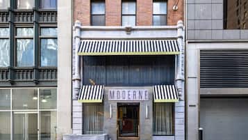 A building with a storefront labeled 'MODERNE' featuring a classic architectural style with a brick facade, large windows, and a striped awning.