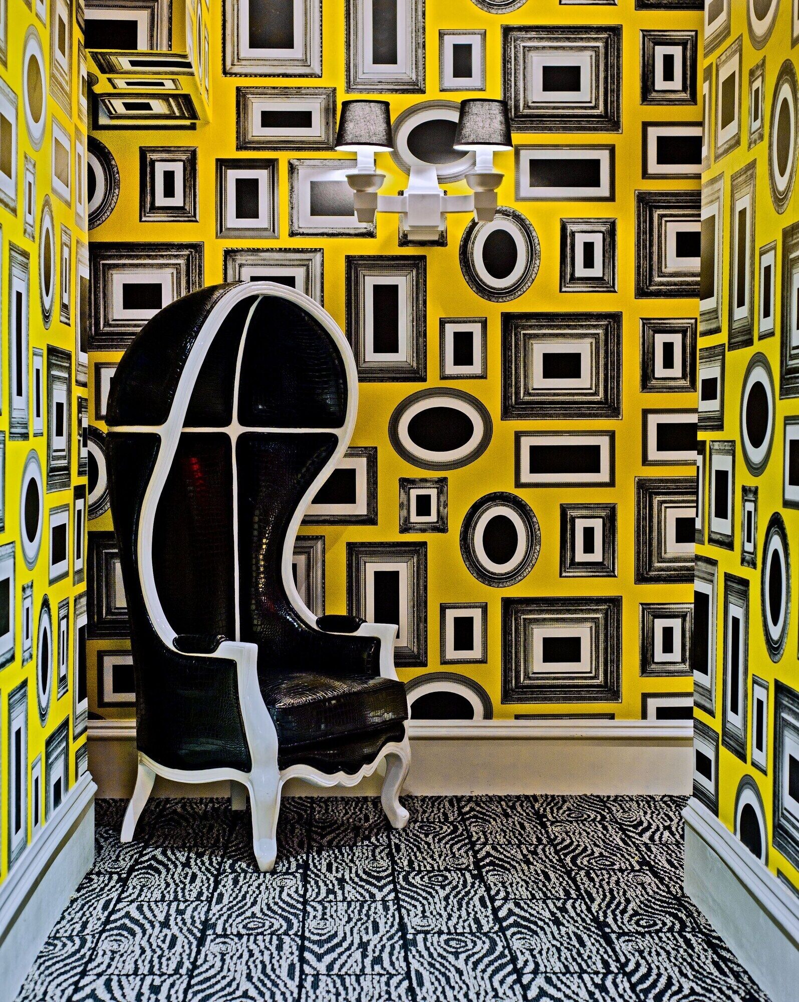 A room with a patterned yellow wall, a black and white chair, and a patterned floor.