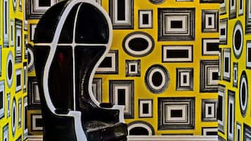 A room with a patterned yellow wall, a black and white chair, and a patterned floor.