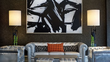 A modern living room with a tufted sofa, two side tables, and a large abstract painting.