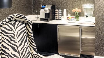 A kitchenette with a coffee maker, sugar, and a fruit bowl.
