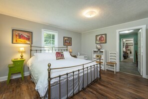 A bedroom with a bed, green nightstand, white lamp, and a wooden floor. - Little Rock Creek Cottage on Trout Stream (Bakersville)